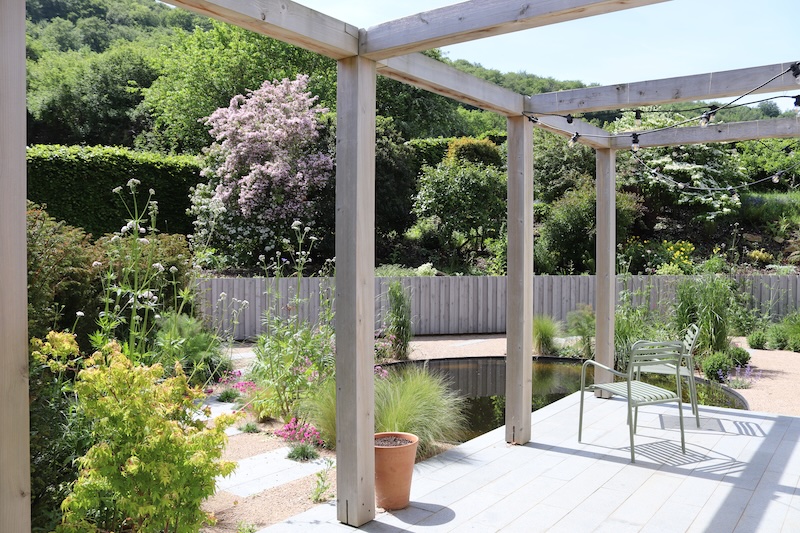 Landscaped garden patio with timber pergola, pond and planting